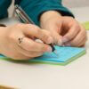 a person writing on a notepad with a pen